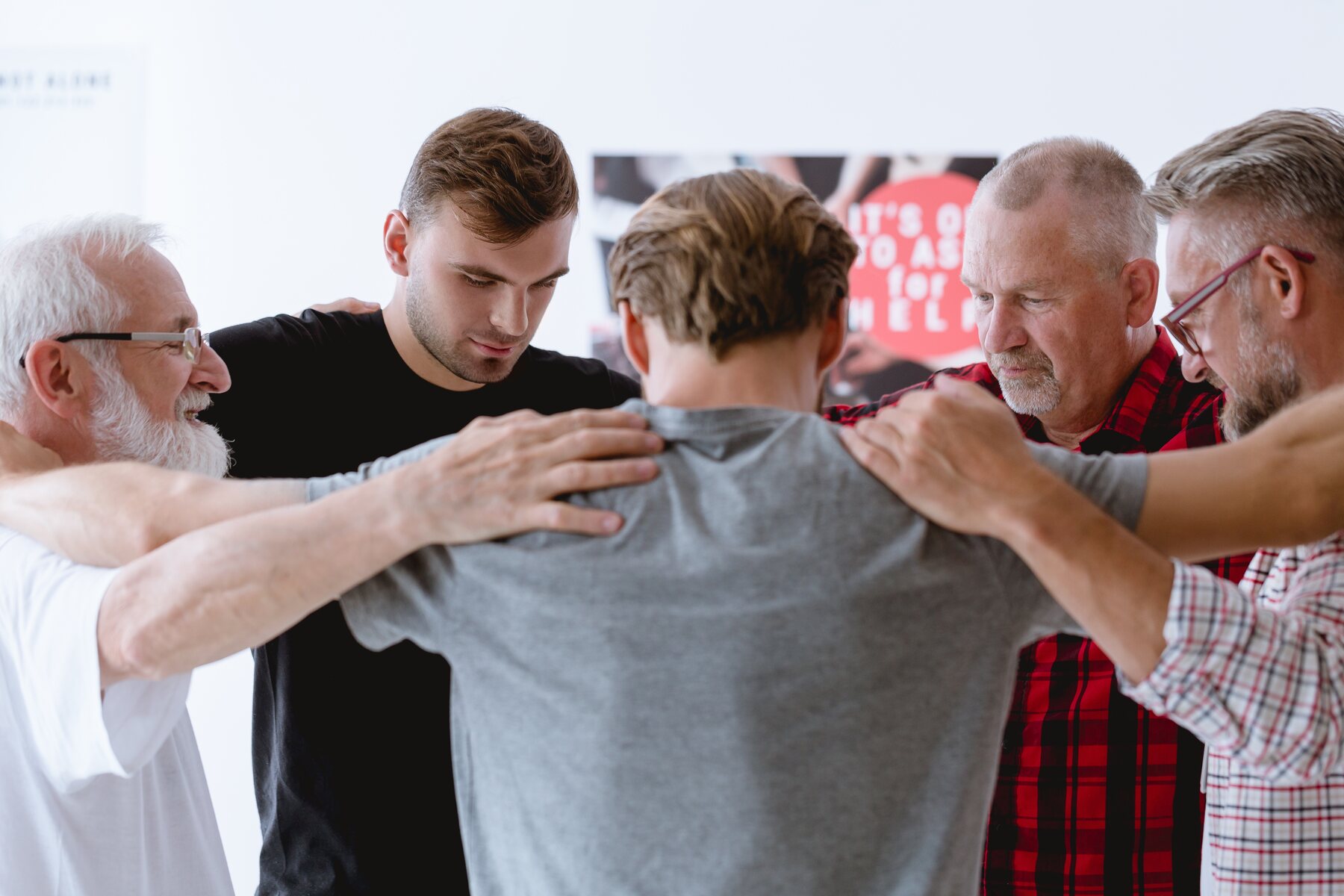 A small group of men supporting one another in prayer