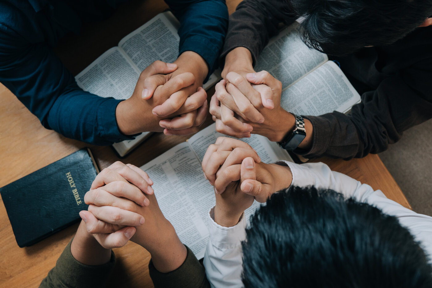 Friends gathered around an open Bible in prayer
