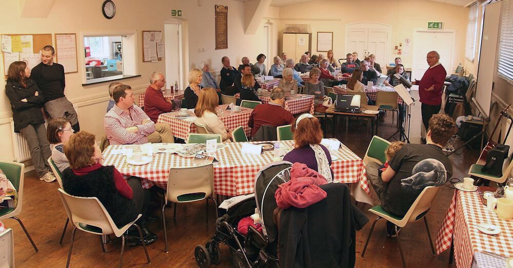 Men and women gathered around tables for a welcoming parish community meeting